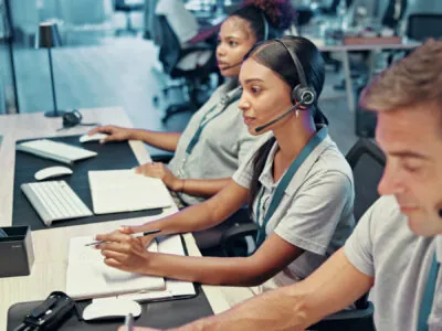 Emergency, service and people on computer with headset for security, dispatcher and operator. Telecommunication, surveillance and first responders with monitor for incident report, contact and help Security dispatch operators wearing headsets in a telecommunications monitoring center, coordinating incident reports and first-responder support